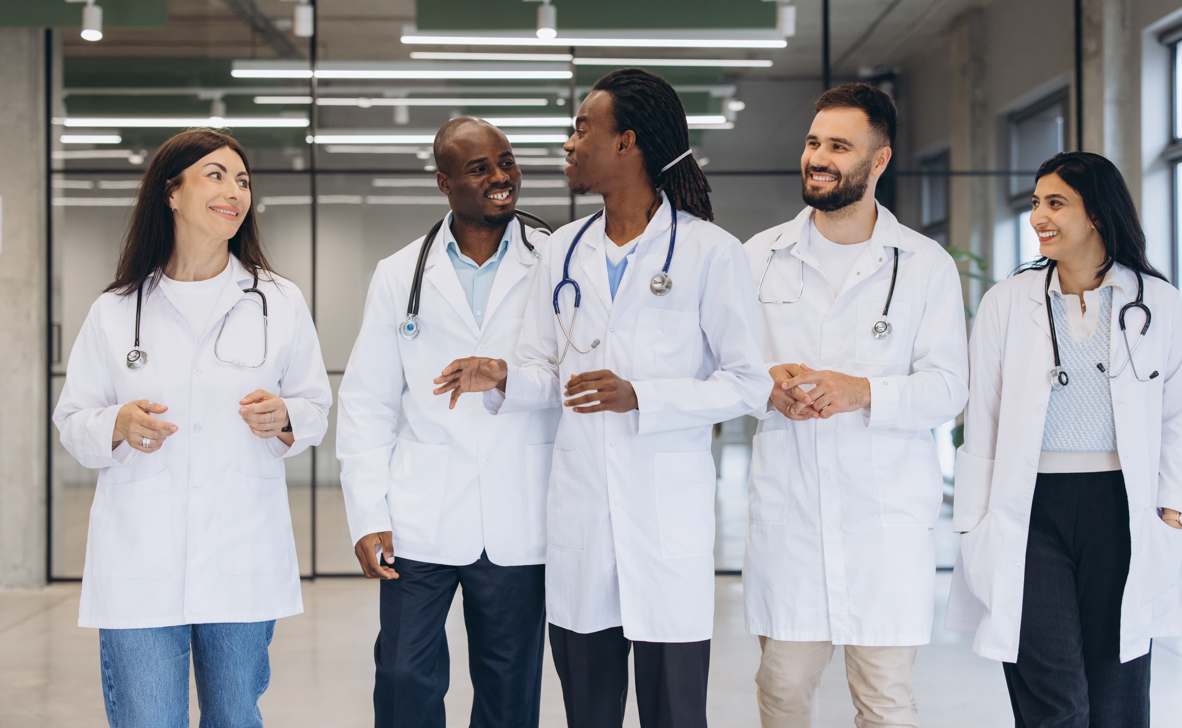 Five physicians walking together through a hospital corridor